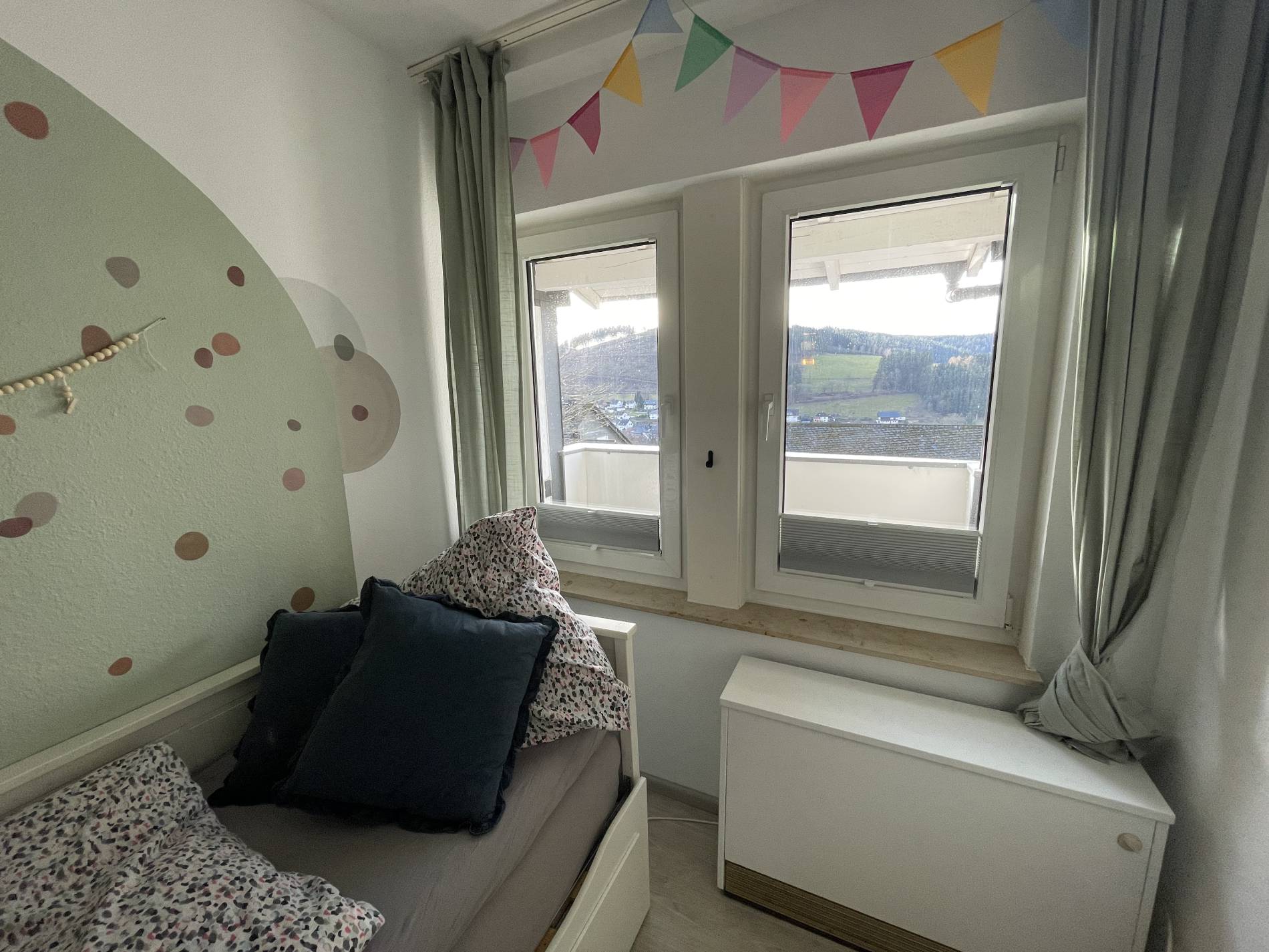 Liebevoll gestaltetes Kinderzimmer mit Wimpelkette und Bergblick